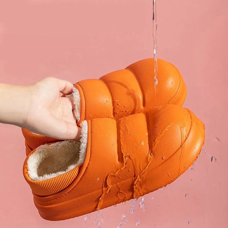 A pair of yellow EVA sleeve-style slippers with a plush lining and a textured non-slip sole, on a wooden floor.