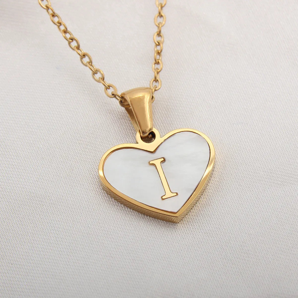 Gold-plated clavicle necklace with a white shell heart pendant, personalised with a letter from A to Z.