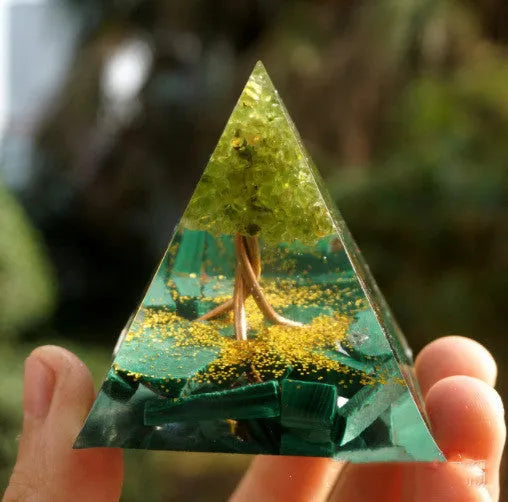 A small 6cm clear epoxy resin pyramid ornament containing pieces of natural crystal gravel on a flat surface.