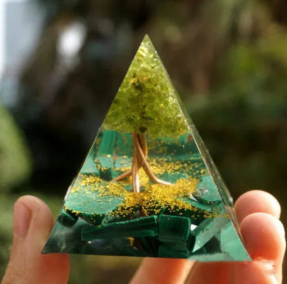 A small 6cm clear epoxy resin pyramid ornament containing pieces of natural crystal gravel on a flat surface.
