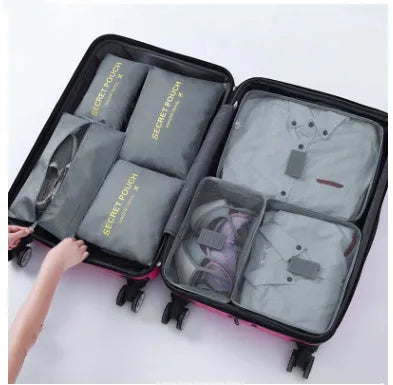 Set of six coloured nylon packing cubes and flat pouches for travel organisation.