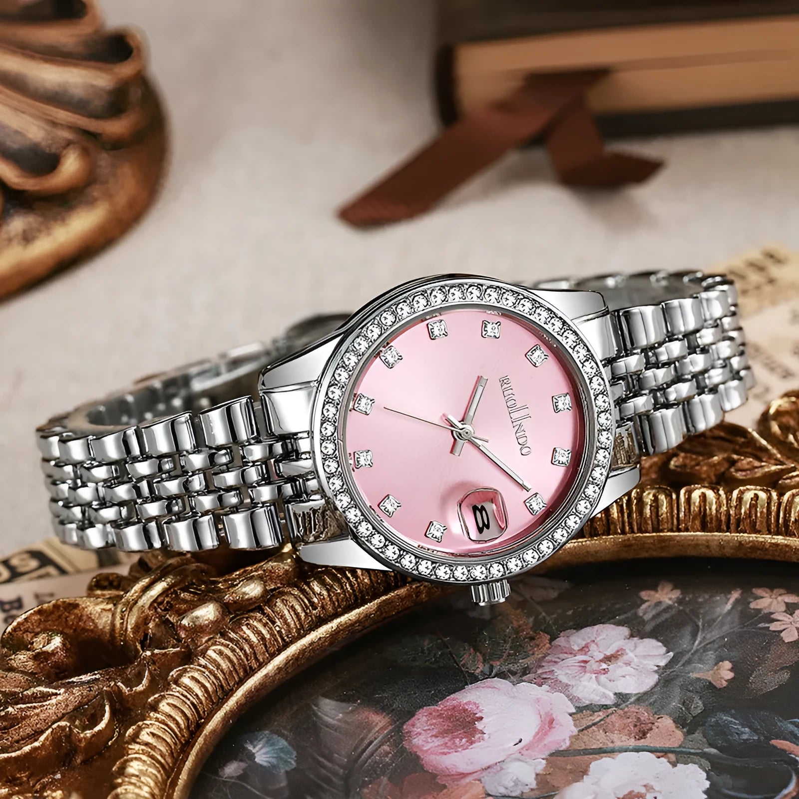 Women's silver alloy calendar watch with quartz movement and stainless steel buckle on wrist.