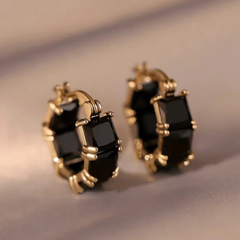 A pair of geometric U-shaped copper earrings with a round zircon stone in a gold-coloured setting.