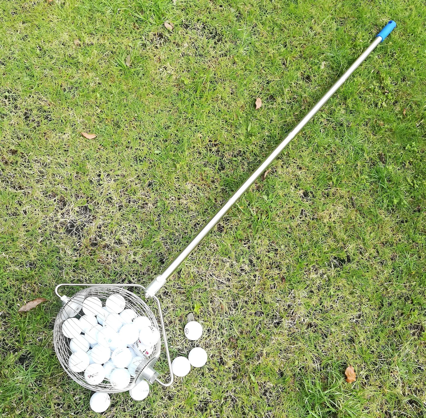 Stainless steel golf ball picker in metallic colour on a green background.