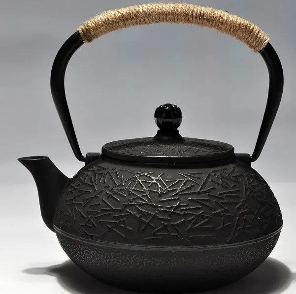 Japanese-style cast iron teapot with lid on a hob, shown in a bronze finish.