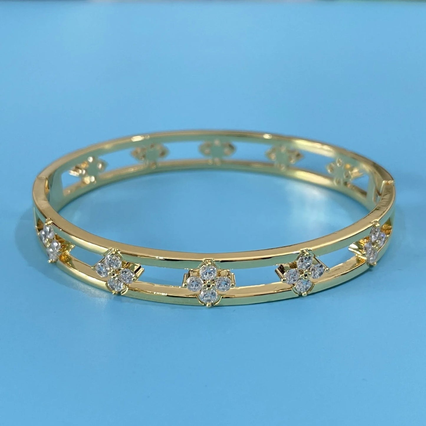 Hollow women's bracelet with four-leaf clover design and inlaid zircon stones in gold or silver finish.
