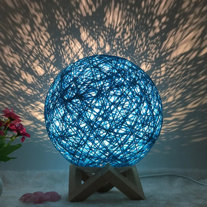 Spherical hand-knitted rattan table lamp with remote control on a wooden desk