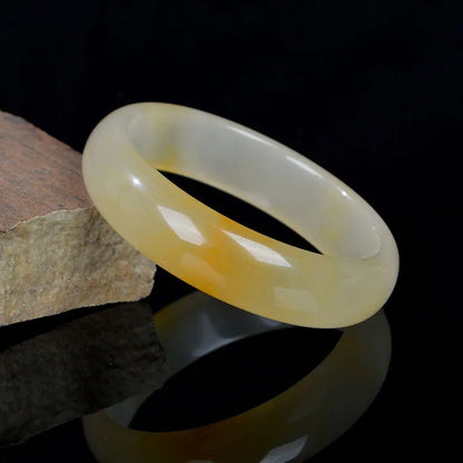 A polished natural light jade bracelet in a traditional Chinese style, shown on a wrist.