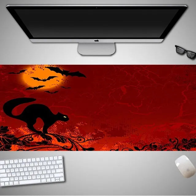 Oversized black mouse pad with Halloween-themed graphic, shown on a wooden desk with keyboard and gaming mouse.