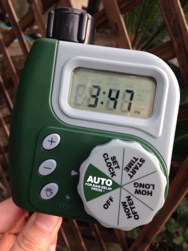 Green garden irrigation controller with LCD display and rotating dial for programming watering schedules
