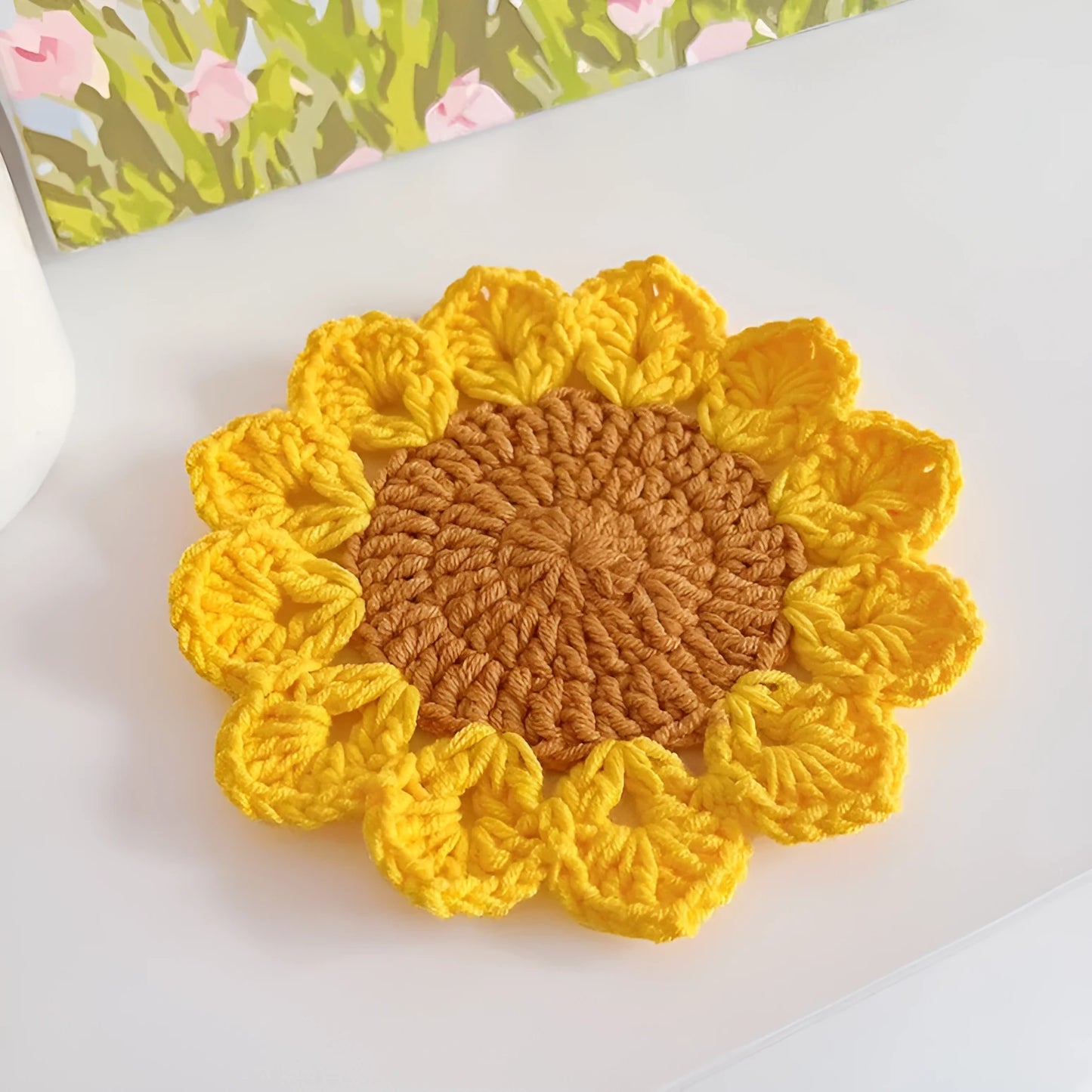 Hand-woven wool flower coaster on a wooden table