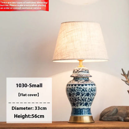 Traditional blue and white Chinese ceramic table lamp with a cloth shade on a bedside table.