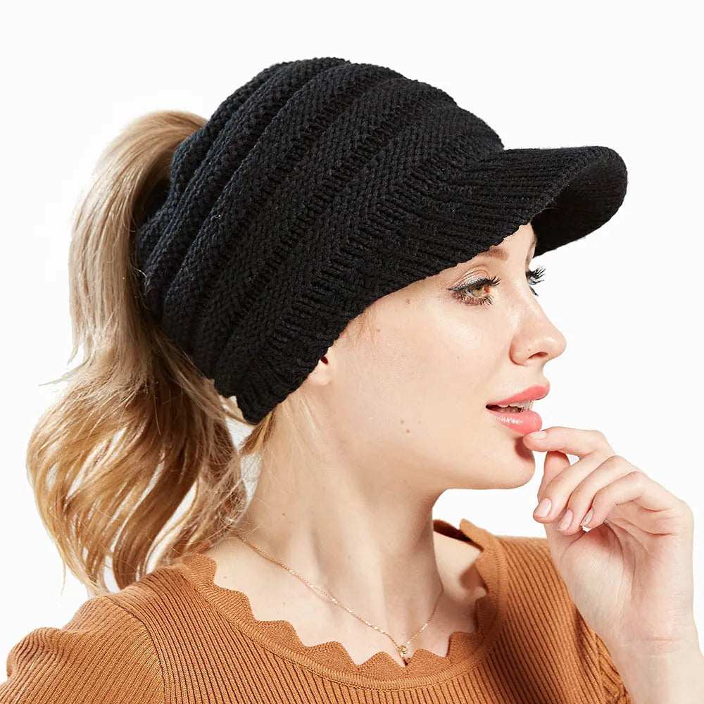 Woman wearing a light grey knitted ponytail beanie with her ponytail pulled through the hole in the back.