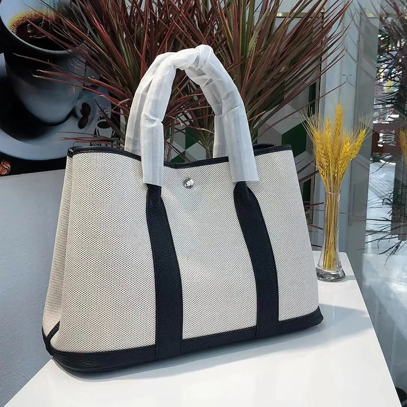 Genuine leather and canvas women's tote bucket bag in black, shown with a soft carry handle.