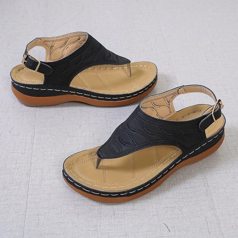 Women's wedge heel flip flop sandals in black with adjustable back strap on a light background