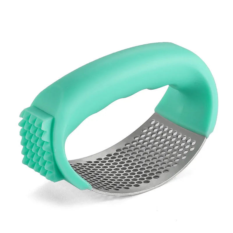 Stainless steel garlic press with coloured handles in a modern design, shown on a kitchen counter.