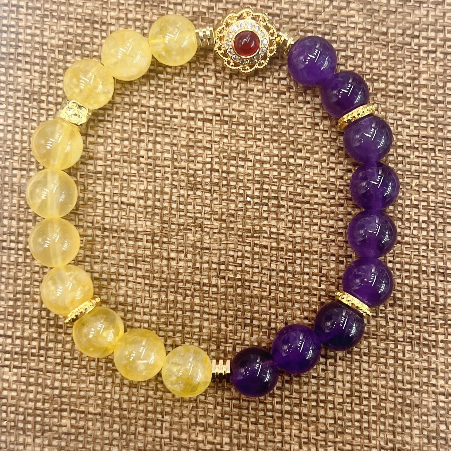 Handmade women's crystal bracelet in yellow and purple colours on a wrist.