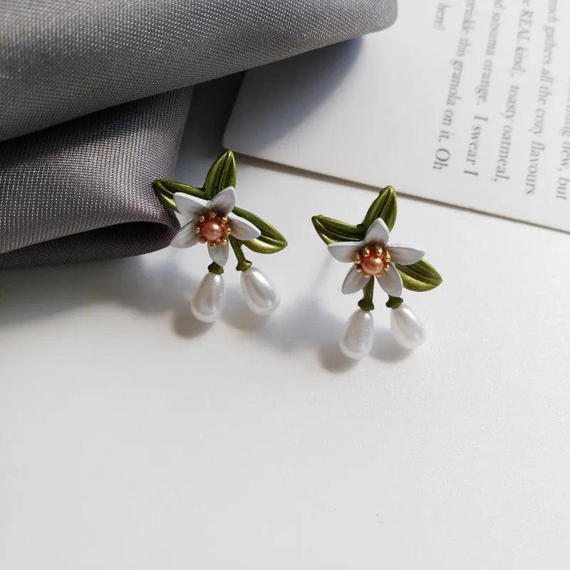 A pair of alloy flower ear studs and a pair of matching flower ear clips with a sterling silver needle detail.