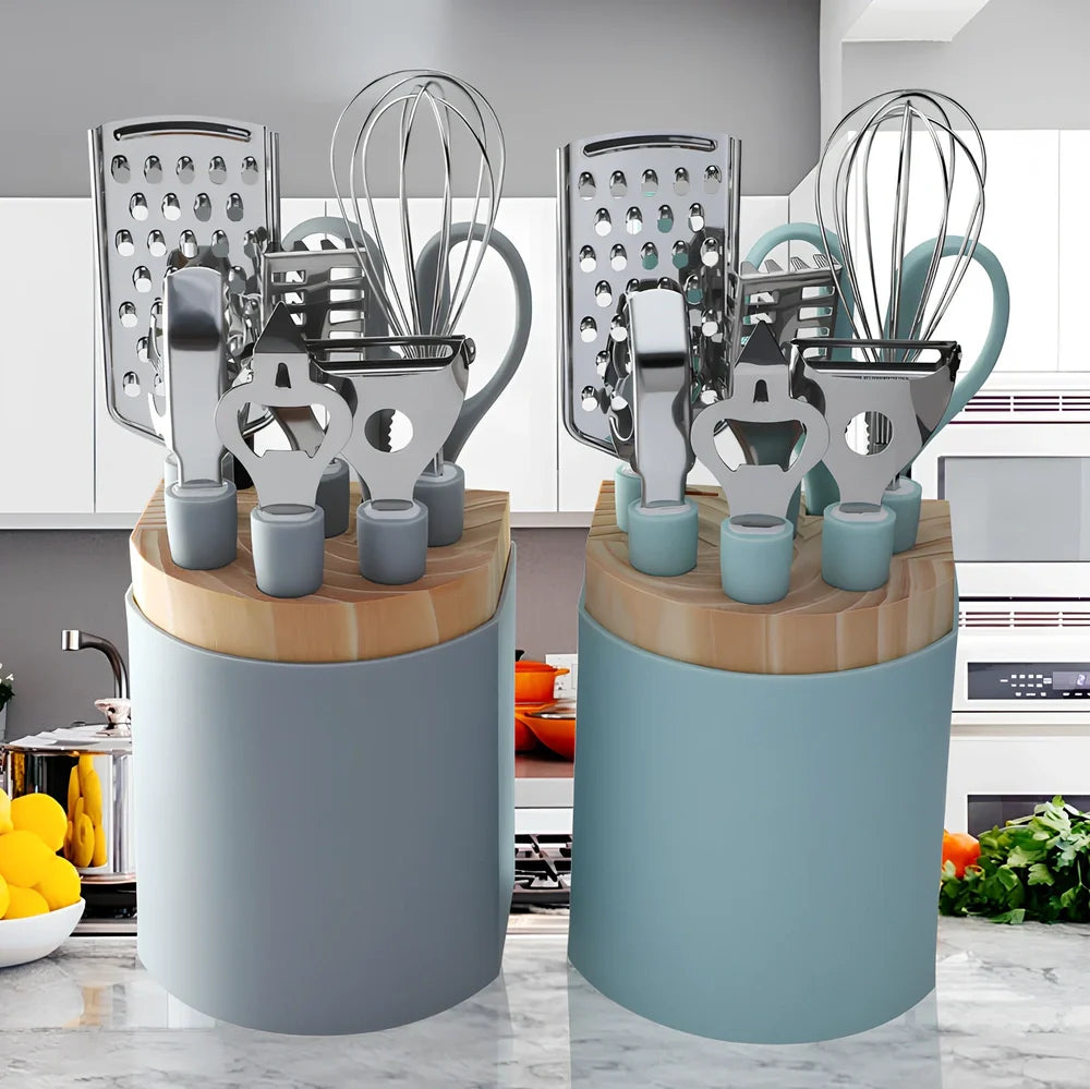 Stainless steel kitchen utensil set with whisk, grater, peeler, scissors and other tools on grey background