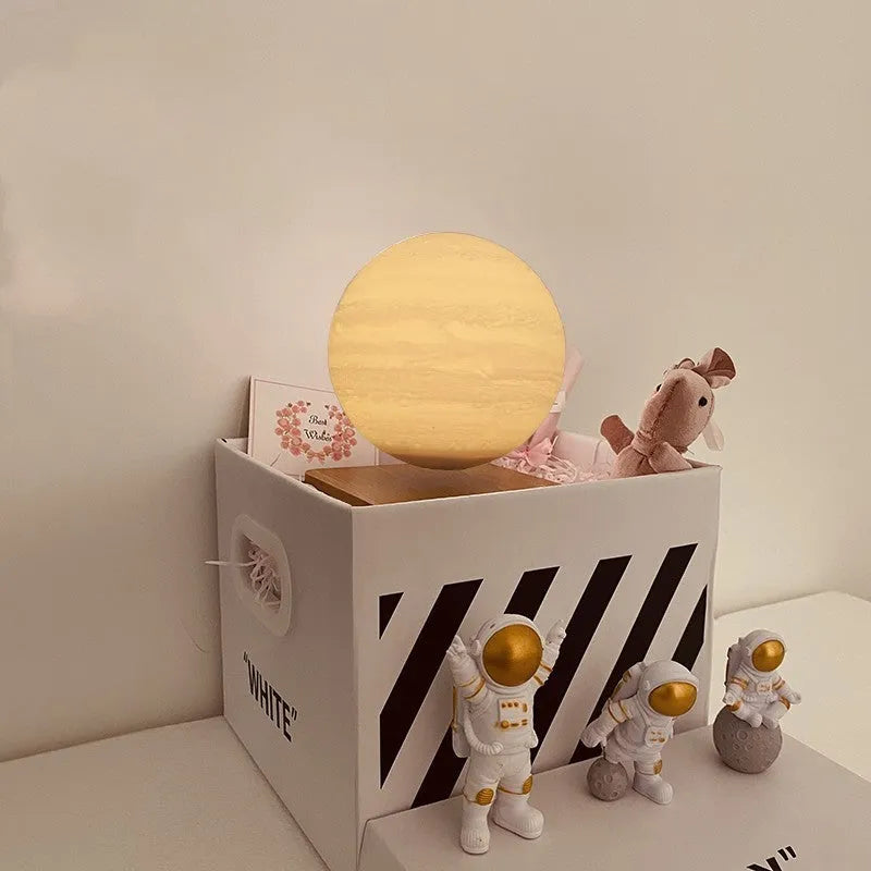 Maglev floating night light with glowing moon and planet designs on a table.