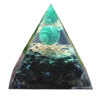 A small 6cm clear epoxy resin pyramid ornament containing pieces of natural crystal gravel on a flat surface.