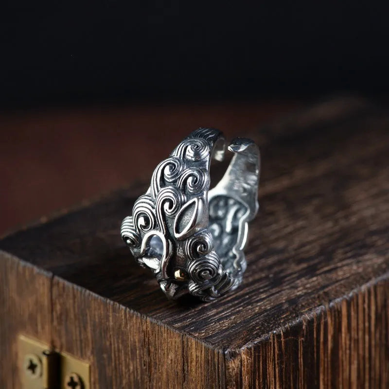 Silver open-style ring with a detailed raised jibeast animal pattern on a model's finger.