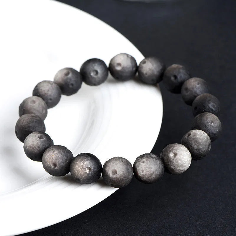 Natural obsidian crater ball bracelet with grinding treatment showing smooth bead texture in silver or golden meteorite colours