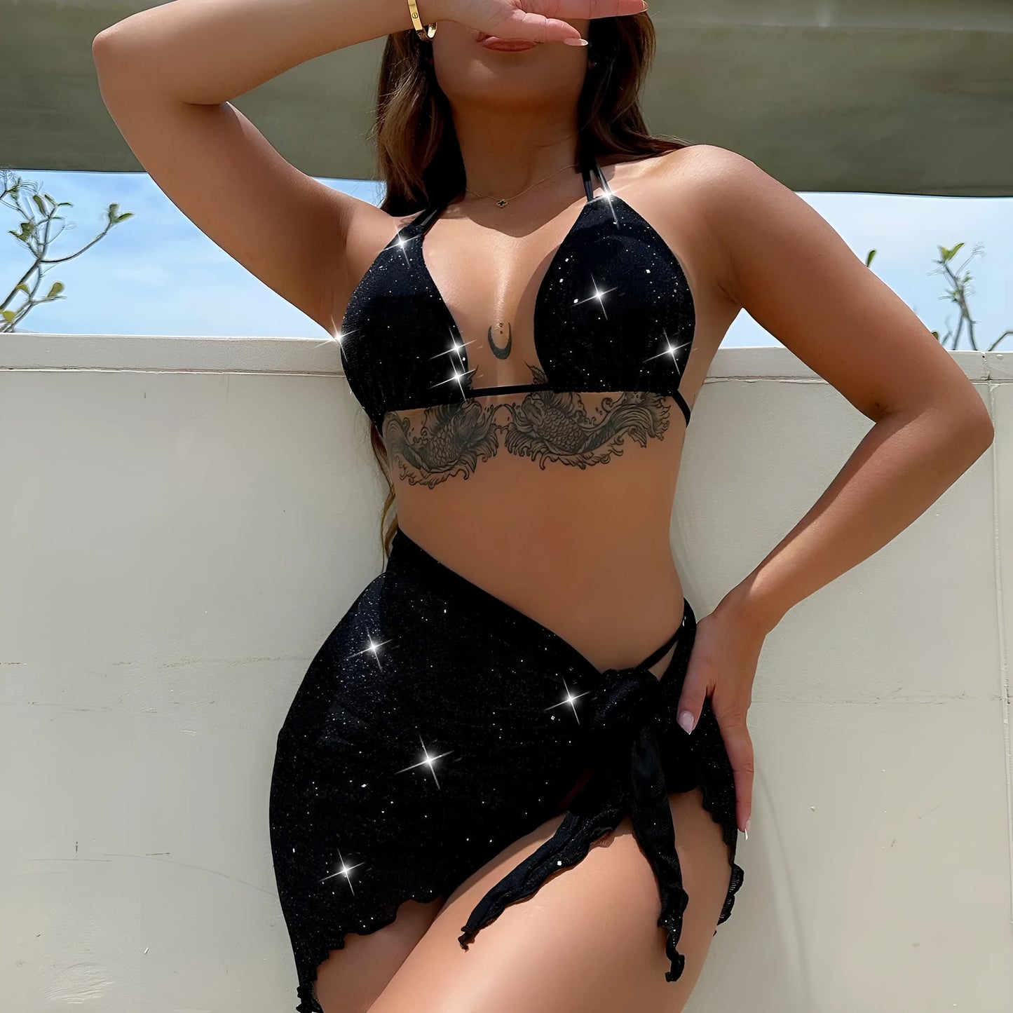 Black three-piece swimsuit bikini set with a top and shorts laid flat.