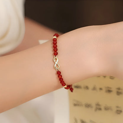Hand-woven red agate beads bracelet with lucky charm in ethnic style, showing diamond-shaped beads.