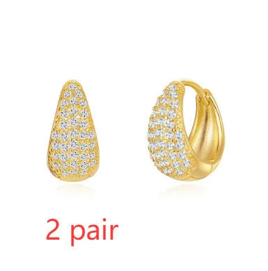 A pair of golden geometric clip-on earrings with a round design element on a white background.