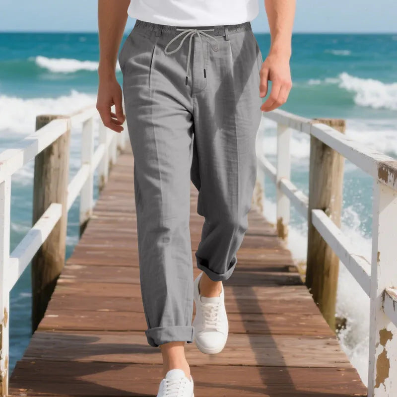 Men's light beige linen trousers with a loose straight leg and drawstring waist on a hanger.