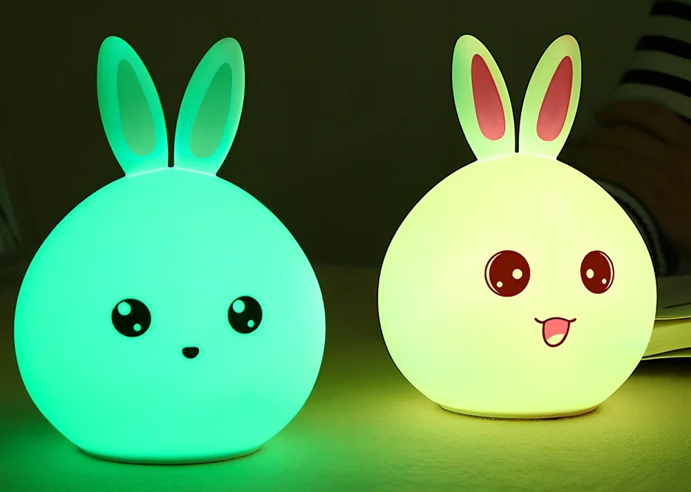 White silicone rabbit night light with USB charging cable showing touch sensor area and colourful LED illumination