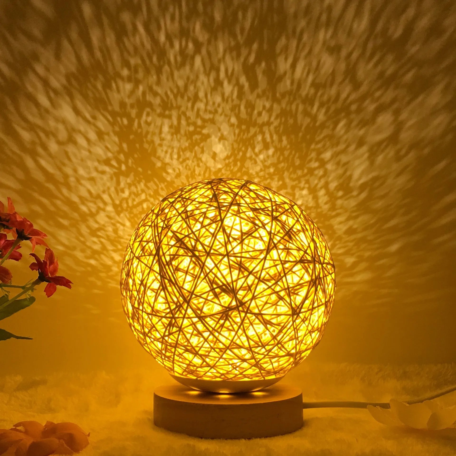Spherical hand-knitted rattan table lamp with remote control on a wooden desk