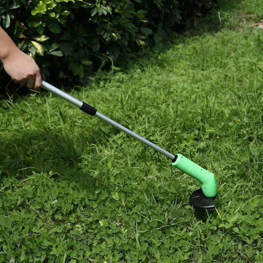 Cordless handheld lawn trimmer with green housing, extension pole, debris shield, and pack of zip ties on a garden lawn.
