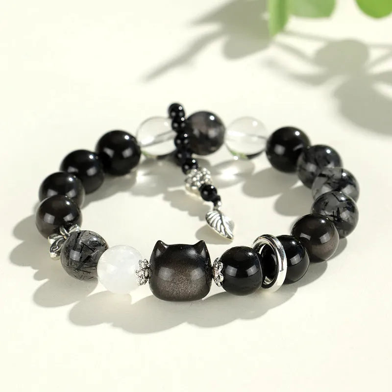 Silver stone crystal bracelet with diamond-shaped fox, cat head, and planet charms on white background.