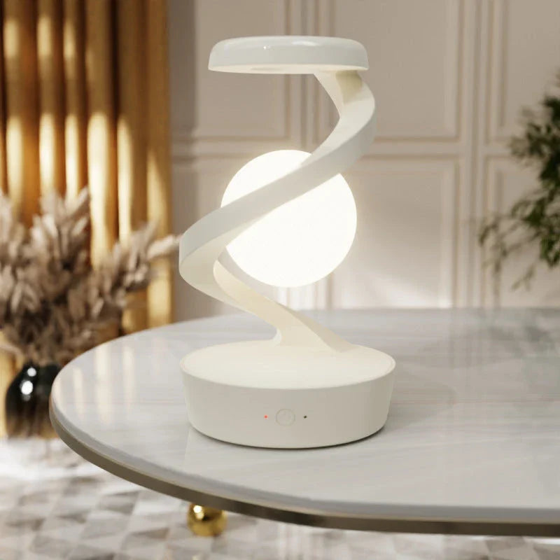 A rotating moon-shaped desk lamp with a wireless charging pad for smartphones, featuring a sleek and modern design.