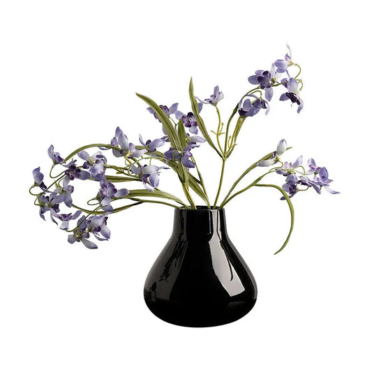 Black ceramic round belly vase with coloured glaze finish and white orchid flowers on wooden table