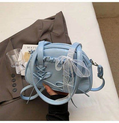Milky white women's shoulder handbag with a large bandage bow and visible stitching, showing the internal phone pocket.