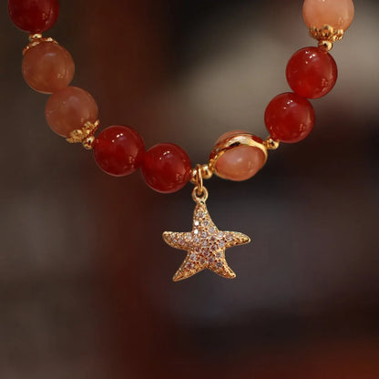 Women's handmade red agate and sunstone bracelet with ethnic charms