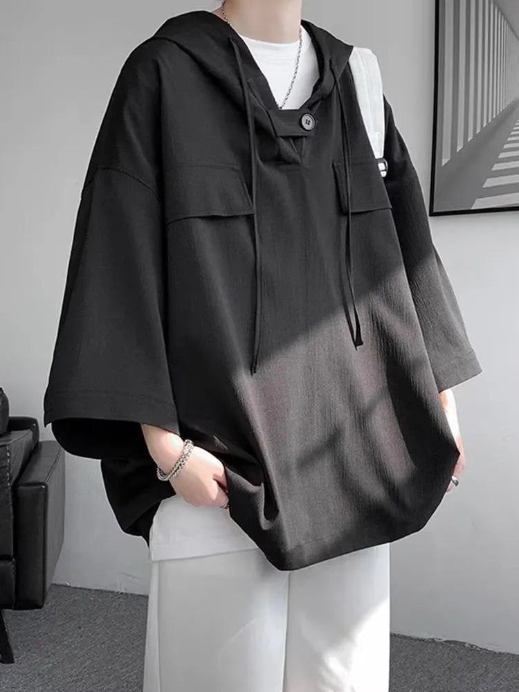 A man wearing a loose-fit black hooded short sleeve t-shirt for summer.