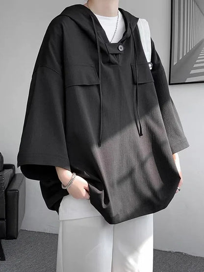 A man wearing a loose-fit black hooded short sleeve t-shirt for summer.