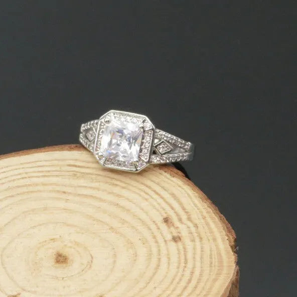 Geometric platinum-coloured copper ring with an inlaid zircon stone, showing its hollow quadrilateral design.