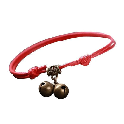 A small dog's nylon rope halter collar with a brass bell and buckle on a black background.