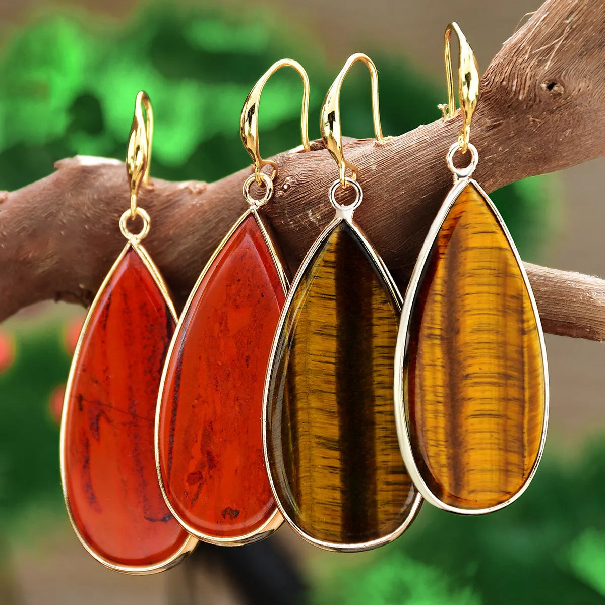 Close-up of long, polished tigereye stone drop earrings with a fishhook clasp on a neutral background.
