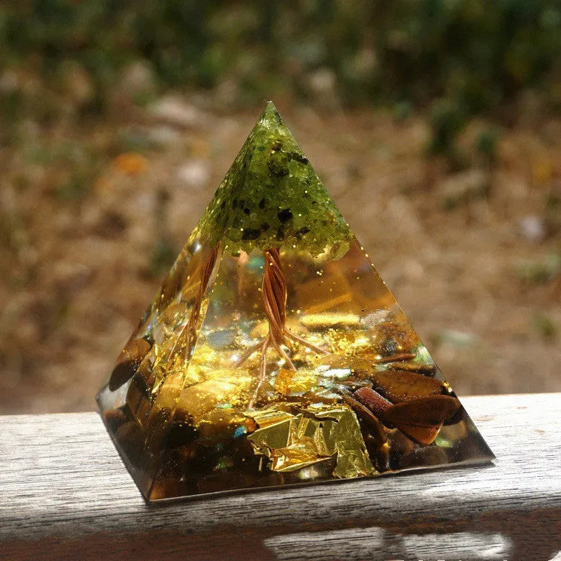 A small 6cm clear epoxy resin pyramid ornament containing pieces of natural crystal gravel on a flat surface.