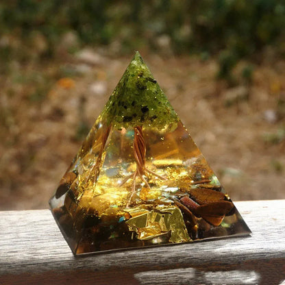 A small 6cm clear epoxy resin pyramid ornament containing pieces of natural crystal gravel on a flat surface.