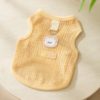 Green knitted cat clothing with a cartoon bear patch, showing hollowed-out breathable design.