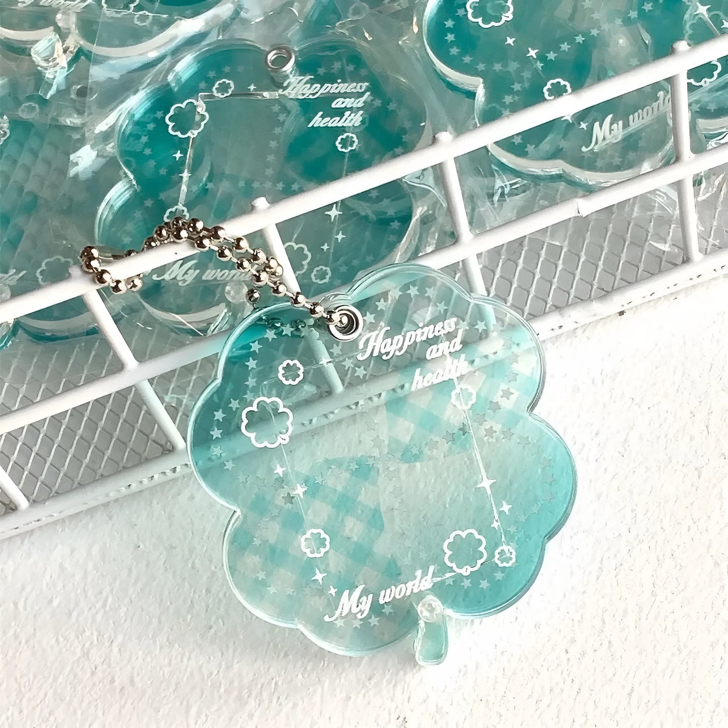 Blue, green, and mint green four-leaf clover acrylic pendant keychain on a metal ring.