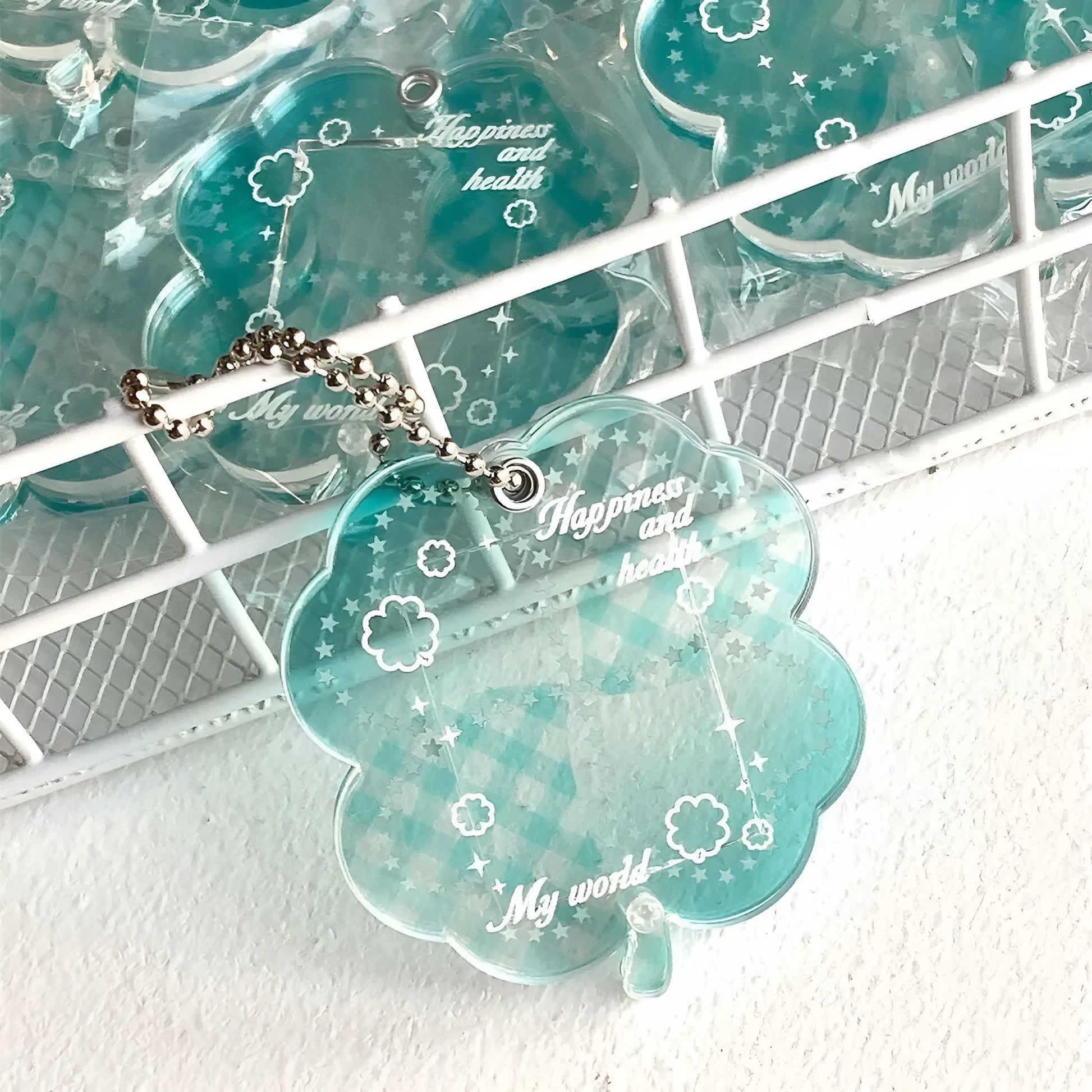 Blue, green, and mint green four-leaf clover acrylic pendant keychain on a metal ring.