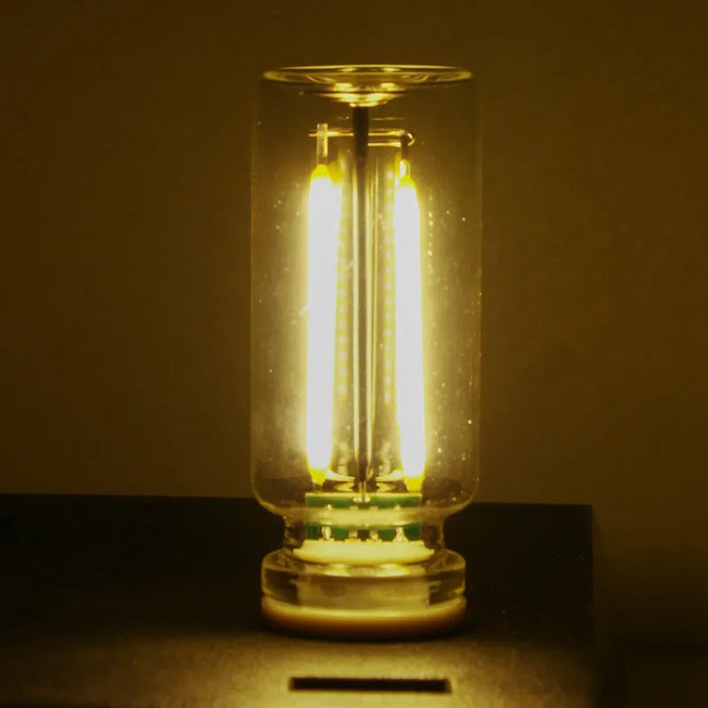 Small transparent glass USB touch night lamp with warm white light on a surface.